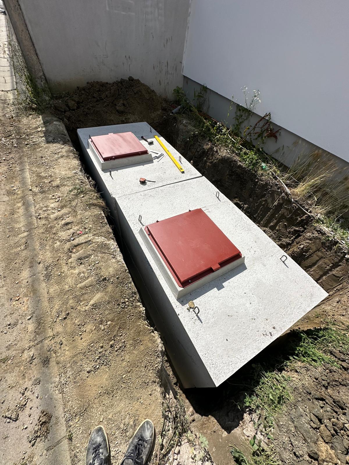 Vodomjerno okno s dva crvena poklopca postavljeno u iskop uz objekt